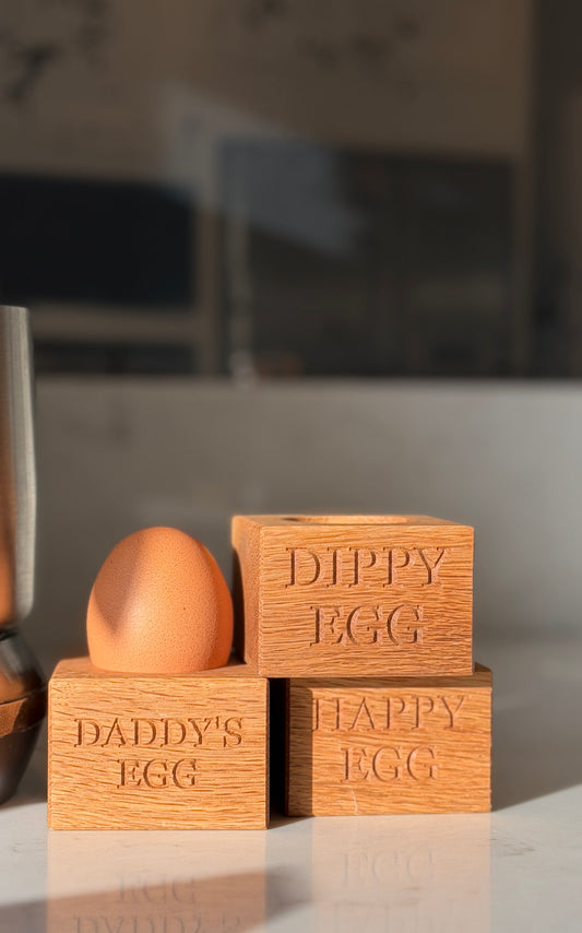 Wooden blocks labeled 'Daddy's Egg' and 'Happy Egg' with a brown egg within a kitchen setting